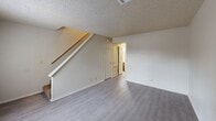 Located at 11310 E 23rd St in Tulsa, Oklahoma, this two-story home offers a practical and well-organized layout across two floors. The main level houses the living room, kitchen, a hallway, and laundry facilities, while the upper level is dedicated to the bedrooms and bathrooms.

The living room features light gray laminate flooring and neutral walls beneath a textured ceiling, creating a clean and open feel. A staircase leads to the upper level, and a pass-through window connects the living area to the kitchen — a functional design detail that enhances the sense of openness. The kitchen is equipped with warm oak cabinetry, light countertops, a white range, and a refrigerator. A dedicated laundry room with side-by-side washer and dryer hookups adds everyday convenience.

Upstairs, the spacious primary bedroom is carpeted and includes generous closet space with dual sets of six-panel bifold doors. A second bedroom also features carpet flooring and a window that brings in natural light. The three bathrooms are finished with wood-tone vanity cabinetry, light countertops, and textured walls. Throughout the home, textured ceilings are consistent across both levels, contributing to the cohesive interior character of this Tulsa residence.