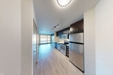 Located at 1111 E Union St in Seattle's vibrant Capitol Hill neighborhood, this modern one-bedroom, one-bathroom unit offers a well-designed layout with contemporary finishes throughout. Light wood-tone flooring runs continuously across the entire floor plan, creating a cohesive and clean aesthetic.

The open-concept kitchen and living area serves as the heart of the unit. The kitchen is outfitted with dark espresso cabinetry, stainless steel appliances including a refrigerator, electric range, microwave, and dishwasher, complemented by white countertops and a stainless steel sink. Track lighting highlights the kitchen, which flows naturally into the living area toward a large floor-to-ceiling window that frames views of the surrounding Seattle cityscape.

The bedroom features a bold teal accent wall that adds a pop of color against neutral tones, and a generous window that fills the room with natural light while offering additional urban views. Two closets provide ample storage throughout the unit.

The bathroom is clean and modern, featuring a glass-enclosed shower stall, a dark-cabinetry vanity, and wood-tone flooring that echoes the rest of the unit. The overall design is minimal and contemporary, making efficient use of the available space while maintaining a bright and functional living environment.
