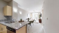 This efficiently designed 610-square-foot, one-bedroom, one-bathroom apartment is laid out across a single floor, offering a cohesive and functional living experience. The open-concept kitchen and living room serves as the heart of the unit, featuring a kitchen equipped with stainless steel appliances, light wood cabinetry, granite countertops, a tile backsplash, track lighting, and a breakfast bar peninsula with hardwood flooring. The adjoining living area is carpeted and bathed in natural light, with a ceiling fan overhead and direct access to a private balcony through a glass-paneled door. The bedroom spans 130 square feet and includes carpet flooring, a large window with outdoor views, and access to two dedicated closets for ample storage. The full bathroom is notable for its elongated layout, featuring a single-sink vanity with a white countertop, light wood cabinetry, a large mirror, hardwood-style flooring, and a tiled shower-tub combination with decorative accent tiles. Neutral warm-gray tones throughout the unit create a calm and cohesive ambiance, while consistent natural light from multiple windows enhances the overall sense of space.