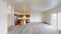 This 760-square-foot, one-bedroom, one-bathroom apartment (Unit 204) at 4685 49th Ave S in Fargo, ND is designed for practical, comfortable living on a single floor. The open-concept kitchen and living area forms the heart of the unit. The kitchen features warm honey-toned cabinetry extending to the ceiling, stainless steel appliances including a refrigerator, range, microwave, and dishwasher, a central island with countertop seating, a double-basin sink, and durable hardwood-style flooring. The adjoining living area is carpeted and receives natural light through a sliding glass door that opens to an outdoor view, complemented by baseboard heating along the perimeter walls. The primary bedroom measures 160 square feet, is carpeted, and includes a window overlooking the exterior. The full bathroom includes warm wood vanity cabinetry, a wide vanity mirror with an overhead light bar, tile-style flooring, and a standard tub-shower combination. A dedicated in-unit laundry room accommodates a full-size washer and dryer with additional wire shelving above. A separate closet provides additional storage. The unit maintains a neutral, light-toned interior throughout.