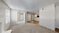 Located at 18050 Kelly Boulevard in Dallas, TX, this 2-bedroom, 2-bathroom home offers a thoughtfully designed single-floor layout with a comfortable and functional feel throughout. The living room serves as a welcoming centerpiece, featuring a classic white brick fireplace, soft carpeting, a textured ceiling, and windows fitted with blinds that allow natural light to filter in. The space flows openly into the dining area and kitchen, creating a seamless entertaining environment. The galley-style kitchen is well-appointed with white cabinetry, dark granite-style countertops, wood-look flooring, a stainless steel sink, and black appliances including a refrigerator and dishwasher. A dedicated pantry adds to the kitchen's practical storage capacity. The primary bedroom is generously sized, featuring plush carpet, a ceiling fan, a walk-in closet, and a private en-suite bathroom. The second bedroom also offers carpet flooring, a ceiling fan, and a bright window. Both bathrooms are clean and functional, with one featuring a tiled shower-tub combo and wood-look flooring. Additional highlights include a dedicated office, an in-unit laundry room with washer/dryer hookups and shelving, and five closets providing exceptional storage throughout the home.