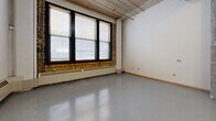 Located at 200 10th Street East in Saint Paul, Minnesota, this single-floor loft unit blends industrial character with functional living. The open-concept main area serves as a combined living, dining, and kitchen space, anchored by polished concrete floors that reflect natural light throughout. Exposed structural columns, visible ductwork, and a corrugated metal ceiling speak to the building's industrial heritage, while large windows with a brick surround allow generous natural light to fill the space and offer views to the exterior.

The kitchen is well-appointed with rich, dark wood cabinetry extending both above and below the countertops, a double-basin stainless steel sink, a full suite of white appliances including a range, dishwasher, refrigerator, and microwave, and ample counter space for meal preparation.

The bathroom features a clean, functional layout with a matching dark wood vanity, dual sinks with a wide mirror, a full soaking tub with shower, and grab bars. Two closets provide practical storage solutions. The unit's open floor plan maximizes the sense of space, while the raw architectural details lend it a distinctive urban loft aesthetic well-suited to city living in downtown Saint Paul.
