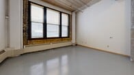 Located at 200 10th Street East in Saint Paul, Minnesota, this single-floor loft unit blends industrial character with functional living. The open-concept main area serves as a combined living, dining, and kitchen space, anchored by polished concrete floors that reflect natural light throughout. Exposed structural columns, visible ductwork, and a corrugated metal ceiling speak to the building's industrial heritage, while large windows with a brick surround allow generous natural light to fill the space and offer views to the exterior.

The kitchen is well-appointed with rich, dark wood cabinetry extending both above and below the countertops, a double-basin stainless steel sink, a full suite of white appliances including a range, dishwasher, refrigerator, and microwave, and ample counter space for meal preparation.

The bathroom features a clean, functional layout with a matching dark wood vanity, dual sinks with a wide mirror, a full soaking tub with shower, and grab bars. Two closets provide practical storage solutions. The unit's open floor plan maximizes the sense of space, while the raw architectural details lend it a distinctive urban loft aesthetic well-suited to city living in downtown Saint Paul.