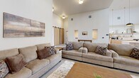 Located at 2507 Orogrande Ln in Caldwell, Idaho, this single-floor community space impresses with its open-concept layout and dramatic vaulted ceilings that amplify the sense of volume and airiness throughout. Large windows and glass double-entry doors flood the interior with abundant natural light, creating a bright and welcoming atmosphere.

The fully equipped kitchen is a standout feature, showcasing warm natural wood cabinetry, sleek white quartz countertops, open floating shelves, stainless steel appliances, and a generous island with bar seating. A series of stylish pendant lights — including bold black dome fixtures and elegant gold glass pendants — add visual interest and warmth to the cooking and prep areas.

The lounge area is thoughtfully arranged with comfortable upholstered sofas, a wood coffee table, and area rugs over polished tile floors. A distinctive sage green wainscoting accent wall with coffered panel detailing anchors the seating zone and provides a refined, layered design element alongside a wall-mounted flat-screen TV. A sliding barn door adds a modern-rustic touch near the rear of the space.

A separate dining area with a table and chairs offers additional functionality. The overall palette of whites, natural wood, and muted greens lends the space a clean, contemporary, and inviting character well-suited for gathering and entertaining.