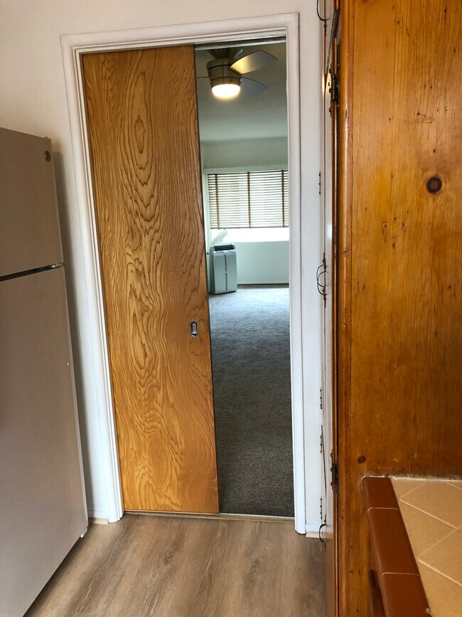 Enter the kitchen through mid century modern classic pocket doors in matching wood. - 7624 Norton Ave