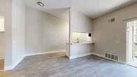 Located at 1440 Barton Rd in Redlands, CA, this efficiently designed single-floor unit makes excellent use of its intimate footprint. The open-concept living room features vaulted ceilings, a ceiling fan, and wood-style plank flooring that runs throughout the entire space, creating a cohesive and modern aesthetic. A sliding glass door fills the living area with natural light and provides direct access to a private balcony with outdoor views of mature trees, enhancing the sense of openness.

The kitchen is thoughtfully separated from the living area by a half-wall pass-through with a stone-look countertop, offering both visual connectivity and functional division. It is equipped with white shaker-style cabinetry, stone-look countertops, a stainless steel sink, and stainless steel appliances including a refrigerator, range, and microwave.

The bathroom features a white vanity with a granite-style countertop, a tub-shower combination, and consistent wood-style flooring. A dedicated walk-in closet with wrap-around hanging rods provides ample storage. Neutral warm-gray walls, textured ceilings, and clean white trim complete the polished, move-in-ready presentation of this Redlands residence.
