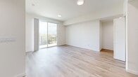 Located at 900 N Ardmore Ave in Los Angeles, CA, this modern 2-bedroom, 2-bathroom unit offers a well-designed, single-floor layout with a clean, contemporary aesthetic throughout. Light-toned hardwood flooring runs continuously across all rooms, enhancing the sense of openness and cohesion.

The open-concept living, dining, and kitchen area forms the heart of the unit. The kitchen is outfitted with two-tone cabinetry — warm wood upper cabinets paired with crisp white lower cabinets — light quartz countertops, a matte black faucet, and a full suite of stainless steel appliances including a refrigerator, range, microwave, and dishwasher. The living area connects directly to a private balcony through sliding glass doors, offering views of palm trees and the surrounding Los Angeles neighborhood.

The primary bedroom is generously sized and features a sliding glass door opening to a second balcony, flooding the room with natural light and tree-lined views. The second bedroom includes large windows and a built-in sliding door closet. Both rooms are bright and finished with the same light hardwood flooring.

The two bathrooms include one full bath with a tub-shower combination and warm wood vanity, and a second bathroom finished with matching flooring and fixtures. The unit also includes a dedicated laundry area, a hallway, and two closets, rounding out a practical and modern living space.