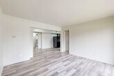 Located at 4050 Lindenwood Dr in Matteson, IL, this 2-bedroom, 1-bathroom unit offers a practical and well-organized single-floor layout. The living area is bright and open, featuring light-toned hardwood-style flooring and neutral white walls that create a clean, airy atmosphere. A sliding glass door leads to a private balcony, bringing in natural light and outdoor views of the surrounding greenery. The kitchen is efficiently designed in a galley style, outfitted with dark espresso cabinetry, light countertops, and a full suite of black appliances including a refrigerator, gas range, and overhead ventilation. Both bedrooms are carpeted for comfort, with the primary bedroom offering a spacious footprint and a sliding mirrored closet door providing convenient storage access. A dedicated closet with built-in shelving and hanging rods adds additional storage capacity. The bathroom is finished with wood-look flooring, a white vanity, and a tub-shower combination featuring large-format gray tile surround. Hallways connect the rooms efficiently throughout the unit, contributing to a cohesive and functional flow across the entire living space.