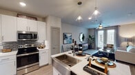 This single-story, one-bedroom, one-bathroom residence in Houston, Texas offers a thoughtfully designed open-concept layout that seamlessly connects the kitchen, dining, and living areas. The kitchen is a standout feature, equipped with stainless steel appliances including a French door refrigerator, electric range, and built-in microwave. White shaker cabinetry with brushed nickel hardware, a mosaic tile backsplash, light quartz countertops, and a deep farmhouse-style sink add both style and functionality. Pendant lighting and recessed fixtures illuminate the space effectively.

The living area is bright and welcoming, with light wood-style flooring, a ceiling fan, and French doors that open to a private balcony with outdoor views. The bedroom features plush carpeting, a ceiling fan, natural light from large windows, and ample space. The bathroom is elegantly finished with a double vanity, white cabinetry, quartz countertops, and wood-look flooring, and leads directly to a spacious walk-in closet with built-in shelving. The overall ambiance is modern and cohesive throughout.