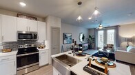 This single-story, one-bedroom, one-bathroom residence in Houston, Texas offers a thoughtfully designed open-concept layout that seamlessly connects the kitchen, dining, and living areas. The kitchen is a standout feature, equipped with stainless steel appliances including a French door refrigerator, electric range, and built-in microwave. White shaker cabinetry with brushed nickel hardware, a mosaic tile backsplash, light quartz countertops, and a deep farmhouse-style sink add both style and functionality. Pendant lighting and recessed fixtures illuminate the space effectively.

The living area is bright and welcoming, with light wood-style flooring, a ceiling fan, and French doors that open to a private balcony with outdoor views. The bedroom features plush carpeting, a ceiling fan, natural light from large windows, and ample space. The bathroom is elegantly finished with a double vanity, white cabinetry, quartz countertops, and wood-look flooring, and leads directly to a spacious walk-in closet with built-in shelving. The overall ambiance is modern and cohesive throughout.