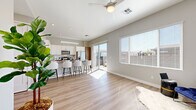 This thoughtfully designed single-floor unit offers a bright, open-concept layout that maximizes every square foot of its compact footprint. Light wood-toned flooring runs continuously throughout, unifying the space and enhancing its airy, modern aesthetic.

The combined kitchen and living area serves as the heart of the unit. The kitchen is outfitted with two-tone cabinetry — warm wood lower cabinets paired with crisp white uppers — complemented by a white subway tile backsplash and gray quartz-style countertops. Stainless steel appliances, including a refrigerator, range, and microwave, complete the functional setup. A peninsula with seating for multiple bar stools provides a natural divider between the kitchen and the open living area, which is bathed in natural light from large windows and a sliding glass door that opens to an outdoor space. A ceiling fan overhead adds comfort and circulation.

The bedroom is generously sized, featuring windows with blinds that allow for adjustable natural light and neutral gray walls that create a calm, versatile atmosphere. The hallway connects the main living spaces efficiently, maintaining a clean flow throughout the unit.

The overall ambiance is clean, contemporary, and light-filled, with a neutral color palette of whites and soft grays that lends itself easily to a variety of interior styles.
