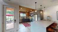 Located in Bentonville, Arkansas, this two-story home presents a thoughtfully designed interior that balances contemporary finishes with warm, natural materials. The kitchen is a standout feature, showcasing wood-planked ceilings and walls that create a cozy yet modern atmosphere. Matte gray cabinetry pairs with light countertops, subway tile backsplash, and stainless steel appliances, while globe pendant lights add a refined touch. A large sliding glass door opens directly to an outdoor deck, filling the space with natural light and providing seamless indoor-outdoor connectivity.

The staircase serves as an architectural focal point, featuring a wood balustrade and an eye-catching geometric chandelier suspended above the landing. The upper level includes a work nook and decorative wall accents. Bedrooms are bright and well-proportioned, with vaulted ceilings in the primary bedroom enhancing the sense of openness, complemented by natural light from multiple windows. A secondary bedroom includes a ceiling fan and warm wood flooring. The bathroom features a walk-in tiled shower with subway tile walls, mosaic tile flooring, and matte black fixtures. The living area offers a relaxed, neutral palette with recessed lighting and a comfortable, curated aesthetic throughout.