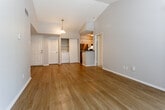 This single-story residence at 11315 Grandview Rd in Kansas City, MO offers a well-organized layout with a mix of functional and comfortable living spaces. The main living area is a standout feature, showcasing vaulted ceilings that lend a sense of openness and volume to the room. Warm wood-look laminate flooring flows throughout the main living and kitchen areas, complemented by neutral gray walls and white trim. A sliding glass door with vertical blinds provides access to an outdoor patio and brings in natural light.

The kitchen is thoughtfully positioned adjacent to the living space and features a breakfast bar peninsula, dark granite-style countertops, white cabinetry, and stainless steel appliances including a refrigerator and range. A pendant light fixture adds a subtle decorative touch overhead.

A dedicated in-unit laundry area is tucked behind louvered closet doors, offering added convenience. The bedrooms are carpeted for comfort, each with neutral tones and natural light from windows. The bathroom includes a tub-shower combination, a dark granite-topped vanity with white cabinetry, and textured walls. Textured ceilings are present throughout, contributing to the home's classic interior character.