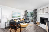 This thoughtfully designed single-floor residence offers a seamless open-concept layout that connects the dining, kitchen, and living areas into one cohesive and functional space. The kitchen is outfitted with light maple cabinetry, white countertops, stainless steel appliances including a refrigerator, range, and microwave, and a central island that bridges the kitchen to the dining area. Wood-style flooring flows throughout the main living spaces, adding warmth and continuity. The living room is bright and inviting, featuring crown molding, a ceiling fan, and a sliding glass door that opens to a private balcony with lush outdoor views.

The residence includes multiple bedrooms, each carpeted for comfort and filled with natural light through large windows. The primary bedroom offers a serene retreat with generous proportions and views of surrounding greenery. Two well-appointed bathrooms serve the home — one featuring a glass-enclosed shower and light quartz countertop, the other with a shower-tub combination. An in-unit laundry area adds everyday convenience. Throughout, the neutral color palette and clean architectural lines create a calm, livable ambiance suited to a variety of lifestyles.