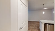 This single-floor unit is designed with a contemporary, open-concept layout that seamlessly connects the kitchen and living areas. The kitchen serves as a central focal point, featuring rich dark wood cabinetry, granite stone countertops, and a subway tile backsplash. A peninsula with an integrated sink and pendant lighting overhead provides both additional prep space and a natural divider between the kitchen and the open living area. Stainless steel appliances, including a range, microwave, and refrigerator, complete the well-appointed kitchen. A dedicated laundry area is also accessible from the kitchen.

The living area is generously sized, bathed in natural light from large windows fitted with blinds, and finished with warm hardwood-style flooring that flows consistently throughout the unit. A ceiling fan adds comfort to this space, while clean white walls and neutral tones create a bright, welcoming atmosphere.

The bathroom features a dark wood vanity with a granite countertop and undermount sink, a framed mirror with overhead lighting, and a full tub-shower combination. The cohesive design elements and quality finishes found throughout the unit contribute to a polished, modern aesthetic.