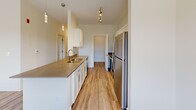 Located in the Copper Creek community in Jackson, Tennessee, this single-floor unit offers a clean, contemporary design throughout. Light-toned, wood-look plank flooring runs consistently across the entire space, complementing the crisp white walls and creating a bright, cohesive aesthetic.

The kitchen is a functional highlight, featuring white shaker-style cabinetry, stone countertops with a built-in sink, and a full suite of stainless steel appliances including a refrigerator, electric range, and microwave. Track lighting and pendant fixtures illuminate the space effectively, while the open layout connects the kitchen to the surrounding living areas.

Multiple living and bedroom spaces are present throughout the unit, each benefiting from natural light provided by white-framed windows fitted with horizontal blinds. Several rooms offer outdoor views of the surrounding landscape, and one room includes direct outdoor access through a glass door, paired with a ceiling fan overhead. Accessibility features are noted in the bathroom, which includes grab bars and hard-surface flooring.

A dedicated laundry room houses a full-size washer and dryer with overhead wire shelving for additional storage. Throughout the unit, clean lines, neutral tones, and consistent finishes contribute to a modern, move-in-ready living environment.
