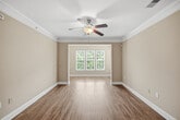 This well-appointed 1,100 square foot single-floor residence offers 2 bedrooms and 2 bathrooms with a thoughtfully designed open layout. The combined kitchen and living area serves as the heart of the home, featuring warm hardwood-style flooring, crown molding, and a ceiling fan with light fixture. The kitchen is equipped with rich wood cabinetry, granite-look countertops, stainless steel appliances including a refrigerator with ice maker, electric range, and microwave, complemented by a peninsula breakfast bar with pendant lighting. The living room benefits from natural light through a window framed by white blinds. Both bedrooms feature plush carpet flooring and ceiling fans, with windows fitted with white blinds providing natural light. The primary bedroom spans 170 square feet and includes a dedicated closet. The primary bathroom offers a double-sink vanity with granite-look countertops, wood cabinetry, a walk-in glass-enclosed shower, and hardwood-style flooring. The second bathroom includes a single vanity and a tub-shower combination. A dedicated laundry room with wire shelving provides added convenience. Neutral warm-toned walls throughout lend the space a clean, cohesive aesthetic.