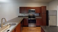 This renovated 2-bedroom, 2-bathroom single-floor residence offers a thoughtfully updated interior with a cohesive blend of modern finishes and functional design. The open-concept living area features rich hardwood-style flooring and crown molding, with a sliding glass door that opens to a private patio, allowing natural light to fill the space and providing views of the surrounding outdoor area.

The kitchen is well-appointed with rich cherry-toned cabinetry, dark granite-style countertops, and a full suite of stainless steel appliances, including a range, over-the-range microwave, dishwasher, and refrigerator. A dedicated laundry area is conveniently accessible directly from the kitchen, housing a full-size washer and dryer.

Both bedrooms are carpeted and finished with neutral tones, offering a comfortable and quiet retreat. Each room includes ceiling fixtures and ample natural light. The two bathrooms are outfitted with dark wood vanities, light countertops, large mirrors, and hardwood-style flooring. One bathroom features a standalone glass-enclosed shower, while the other includes a shower-tub combination, providing flexibility for residents.

Throughout the residence, neutral wall tones, clean white trim, and updated fixtures contribute to a fresh, move-in-ready ambiance.