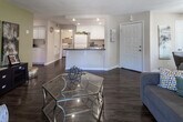 Located at 39930 Whitewood Rd in Murrieta, California, this single-floor residence offers a well-organized layout with comfortable living spaces throughout. The living room serves as the heart of the home, featuring rich hardwood-style flooring, a tile-surround fireplace, and sliding glass doors that open onto a private balcony with outdoor seating — allowing natural light to fill the room. A dedicated dining area with a ceiling fan sits adjacent to the main living space, providing a seamless flow for everyday living and entertaining. The kitchen is equipped with white cabinetry, dark countertops, and full appliances, with direct access to an in-unit laundry room for added convenience. The primary bedroom is a standout space, highlighted by a bold accent wall, plush carpet, a walk-in closet, and an en-suite bathroom featuring a tub-shower combination. A second bedroom offers its own distinct character with a teal accent wall, carpeted flooring, and a bright window. Both bathrooms are finished with hardwood-style flooring, vanities with granite-style countertops, and tub-shower combinations. Throughout the home, colorful accent walls and curated details contribute to a vibrant and welcoming ambiance.