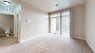 Located at 6720 W 29th St in Greeley, Colorado, this single-story, one-bedroom, two-bathroom residence offers a well-organized layout designed for comfortable everyday living. The kitchen is a functional centerpiece, featuring warm wood cabinetry, granite countertops, black appliances including a refrigerator, range, microwave, and dishwasher, and durable hardwood-style flooring illuminated by track lighting overhead. The kitchen flows into the living area, which is finished with plush carpeting and neutral-toned walls that lend a clean, inviting atmosphere. Sliding glass doors open to a private balcony, bringing in natural light and outdoor views. The bedroom is a well-proportioned retreat with a large window overlooking greenery, soft carpeting, and direct access to a walk-in closet equipped with wire shelving for ample storage. The en-suite bathroom includes a granite-topped vanity with wood cabinetry and a full tub-shower combination with white tile surround and stone-look tile flooring. A second full bathroom provides added convenience for guests. Track lighting accents both the kitchen and living spaces, adding a modern touch to the overall design. The unit presents a cohesive, neutral palette throughout, making it a versatile and move-in ready space.