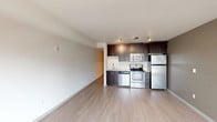 Located at 1111 East Union Street in Seattle's dynamic Capitol Hill neighborhood, this modern single-floor unit offers a clean, open layout designed for efficient urban living. The open-concept living and kitchen area is anchored by light hardwood-style flooring that runs throughout, creating a warm and cohesive feel. A large picture window in the living area fills the space with natural light and frames views of the surrounding Seattle cityscape.

The kitchen is well-appointed with dark espresso-toned cabinetry that extends to the ceiling for ample storage, complemented by light countertops and a classic white tile backsplash. A full suite of stainless steel appliances includes a refrigerator, electric range, built-in microwave, and dishwasher. Recessed track lighting overhead adds focused illumination to the workspace.

The bathroom features a sleek dark wood vanity with an undermount sink, white quartz-style countertop, a large frameless mirror, and bright vanity lighting. The overall palette is clean and neutral throughout. The floorplan also reveals an in-unit washer and dryer, a practical amenity that enhances everyday convenience. The unit's modern finishes and efficient design make it a well-suited option for those seeking contemporary living in one of Seattle's most walkable urban neighborhoods.