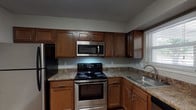 This single-floor Cornwall unit offers a practical and comfortable layout across two bedrooms and two bathrooms. The kitchen is a functional highlight, featuring rich warm-toned cabinetry, granite-style countertops, and a full suite of stainless steel appliances including a refrigerator, electric range, over-the-range microwave, and dishwasher. Wood-look flooring runs through the kitchen, adding warmth and easy maintenance to the space. A window above the sink provides natural light throughout the day.

The spacious living area is carpeted and features neutral-toned walls, a textured ceiling, and a sliding glass door that invites natural light and provides outdoor access. The two bedrooms are also carpeted, with one featuring a ceiling fan and closet, and the other offering dual windows with outdoor views, filling the room with natural light.

The two bathrooms differ in configuration: one includes a tiled walk-in shower with chrome fixtures, while the second features a full tub-shower combination with white tile surround and wood-look flooring. Both bathrooms are finished with clean, simple fixtures. Overall, the unit presents a straightforward and well-maintained living environment suited for everyday comfort.