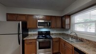 This single-floor Cornwall unit offers a practical and comfortable layout across two bedrooms and two bathrooms. The kitchen is a functional highlight, featuring rich warm-toned cabinetry, granite-style countertops, and a full suite of stainless steel appliances including a refrigerator, electric range, over-the-range microwave, and dishwasher. Wood-look flooring runs through the kitchen, adding warmth and easy maintenance to the space. A window above the sink provides natural light throughout the day.

The spacious living area is carpeted and features neutral-toned walls, a textured ceiling, and a sliding glass door that invites natural light and provides outdoor access. The two bedrooms are also carpeted, with one featuring a ceiling fan and closet, and the other offering dual windows with outdoor views, filling the room with natural light.

The two bathrooms differ in configuration: one includes a tiled walk-in shower with chrome fixtures, while the second features a full tub-shower combination with white tile surround and wood-look flooring. Both bathrooms are finished with clean, simple fixtures. Overall, the unit presents a straightforward and well-maintained living environment suited for everyday comfort.