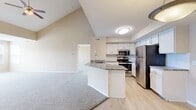 Located at 5694 Calais Ln in Saint Petersburg, FL, this two-story home offers 2 bedrooms and 2 bathrooms across a well-distributed layout. The main floor hosts the primary living areas, including an open-concept kitchen and living room highlighted by soaring vaulted ceilings that lend an airy, expansive feel. The kitchen is well-appointed with granite countertops, white cabinetry, a subway tile backsplash, and a full suite of stainless steel appliances, including a refrigerator, range, and microwave. Light wood-style flooring runs throughout the main living areas, while plush carpet adds comfort to the bedrooms. A dedicated in-unit laundry room with side-by-side washer and dryer provides added convenience. The primary bedroom features impressively tall ceilings and a closet, while the second bedroom on the upper floor benefits from vaulted ceilings, a ceiling fan, and light wood flooring. Bathrooms are finished with granite-topped vanities and white cabinetry. Carpeted staircases with white wood railings connect the two floors. The second bedroom offers multiple windows with views of the surrounding neighborhood, filling the space with natural light.