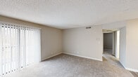 Located at 216 Wind Rd in Greensboro, NC, this single-floor residence offers a well-organized layout with a clean, neutral aesthetic throughout. The open living area is finished with plush wall-to-wall carpeting and a textured ceiling, creating a warm and comfortable atmosphere. A large sliding glass door floods the space with natural light while providing convenient outdoor access. The living area flows seamlessly into a secondary carpeted room, ideal for use as a dining space or additional lounge area, with a ceiling fan overhead and easy access to the rest of the unit. The galley-style kitchen is thoughtfully appointed with white cabinetry, granite-look countertops, a stainless steel sink, classic subway tile backsplash, and stainless steel appliances including a refrigerator, electric range, and over-the-range microwave. Light wood-look flooring adds a modern touch to this functional cooking space. The bedroom offers a quiet retreat with soft carpet, a window with blinds overlooking the outdoors, and ample wall space. The bathroom is well-equipped with a full tub and shower combination featuring a curved curtain rod, a granite-top vanity with an undermount sink, and wood-look flooring, all finished with brushed nickel hardware for a cohesive, contemporary look.