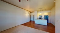 Located at 1187 Harness Rd in Monument, Colorado, this single-floor residence offers a well-designed, open-concept layout that seamlessly connects the living area to the kitchen. The living space features a combination of hardwood-style flooring and plush carpet, with crown molding accents and a ceiling fan providing both style and comfort. A sliding glass door leads to a private balcony, offering scenic views of the surrounding Colorado landscape, including mountain vistas on the horizon.

The kitchen is a functional highlight of the unit, showcasing light wood cabinetry, granite countertops, and a peninsula island with an integrated sink — ideal for meal prep and casual dining. Pendant lighting and track lighting illuminate the space, complementing the black appliance suite that includes a range, over-the-range microwave, and refrigerator.

The bedrooms are carpeted and generously sized, each equipped with a ceiling fan and ample natural light through windows with blinds. The bathroom features a full tub and shower combination with brushed nickel fixtures and tile flooring. Throughout the unit, neutral tones and consistent finishes create a clean, cohesive aesthetic well-suited to the Monument, CO setting.