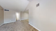This single-floor residence offers a functional and straightforward layout across multiple rooms, finished with a consistent neutral color palette throughout. The living area provides an open feel, enhanced by vaulted ceiling details that add vertical interest and a sense of spaciousness. Natural light enters through windows fitted with horizontal blinds, brightening the carpet-floored space. A ceiling fan is present in one of the bedrooms, contributing to comfortable air circulation.

The bedrooms are carpeted and generously proportioned, each featuring windows that allow natural light in. Some rooms display angled ceiling elements, adding architectural character. The layout, as seen in the 3D floor plan, shows a well-organized arrangement of rooms that maximizes the available footprint.

The galley-style kitchen is efficiently designed, featuring white cabinetry, light-toned countertops, wood-look vinyl flooring, and black appliances including a gas range, dishwasher, and refrigerator. A window above the sink area provides natural light.

Two bathrooms serve the unit, both finished with wood-look vinyl flooring. One bathroom includes a vanity with a mirror, white cabinetry, and a toilet, while the second features a full tub-shower combination with a tiled surround and a window for ventilation.