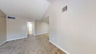 This single-floor residence offers a functional and straightforward layout across multiple rooms, finished with a consistent neutral color palette throughout. The living area provides an open feel, enhanced by vaulted ceiling details that add vertical interest and a sense of spaciousness. Natural light enters through windows fitted with horizontal blinds, brightening the carpet-floored space. A ceiling fan is present in one of the bedrooms, contributing to comfortable air circulation.

The bedrooms are carpeted and generously proportioned, each featuring windows that allow natural light in. Some rooms display angled ceiling elements, adding architectural character. The layout, as seen in the 3D floor plan, shows a well-organized arrangement of rooms that maximizes the available footprint.

The galley-style kitchen is efficiently designed, featuring white cabinetry, light-toned countertops, wood-look vinyl flooring, and black appliances including a gas range, dishwasher, and refrigerator. A window above the sink area provides natural light.

Two bathrooms serve the unit, both finished with wood-look vinyl flooring. One bathroom includes a vanity with a mirror, white cabinetry, and a toilet, while the second features a full tub-shower combination with a tiled surround and a window for ventilation.