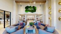 Located at 3065 Champion Ring Rd in Fort Myers, Florida, this generously proportioned single-floor clubhouse is a showcase of contemporary design and curated detail. The grand entrance lobby sets the tone immediately, featuring soaring double-height ceilings with exposed wood beam accents, a sculptural globe chandelier, and floor-to-ceiling windows that bathe the space in abundant natural light while framing views of the lush Florida landscape. A striking live moss wall installation with a neon "Welcome Home" sign serves as a memorable focal point above the main seating area.

The living lounge is warmly appointed with plush, coordinated sofas, layered area rugs, and gold disc wall sconces that lend an art-gallery quality to the space. An adjacent game room offers a full-size billiards table beneath a bold starburst chandelier, a sleek linear fireplace framed in wood paneling with a mounted TV above, and tall windows dressed in sheer floor-length drapes that invite in natural light.

The private dining room is a design highlight, featuring an ornately illustrated ceiling mural, a dramatic multi-arm Sputnik chandelier, a long communal table, and curated abstract wall art. Throughout the space, light tile flooring, teal accent walls, and thoughtfully selected furnishings create a cohesive, resort-inspired ambiance ideal for community gatherings and social events.