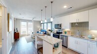 This thoughtfully designed 1-bedroom, 2-bathroom residence offers an efficient and modern single-floor layout that maximizes every square foot. The open-concept living and kitchen area forms the heart of the home, where a central granite-topped island serves as both a prep space and casual gathering point, illuminated by a trio of stylish pendant lights. The kitchen is outfitted with crisp white cabinetry extending to the ceiling, a herringbone-patterned tile backsplash, stainless steel appliances including a side-by-side refrigerator, range, microwave, and dishwasher, all set against warm wood-style plank flooring. The living area flows naturally from the kitchen and benefits from large windows and a sliding glass door that invite abundant natural light. The bedroom is a comfortable retreat featuring a ceiling fan, large windows with outdoor views, and easy access to a dedicated closet and full bathroom. The primary bathroom offers granite countertops, white cabinetry, and a full tub-shower combination with elegant marble-style tile surround. A second full bathroom provides added convenience. Neutral tones, clean lines, and quality finishes create a cohesive and modern ambiance throughout the entire space.