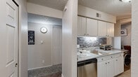 This 1-bedroom, 1-bathroom unit is thoughtfully designed to maximize functionality and comfort throughout its single-floor layout. The open living room is carpeted and bathed in natural light from a large sliding glass door that leads to a private balcony, offering an inviting indoor-outdoor connection. A ceiling fan overhead adds a practical touch to the living space, which flows seamlessly into a dedicated dining area.

The galley-style kitchen is efficiently arranged with white cabinetry, granite-style countertops, a stainless steel sink, a dishwasher, and a full-size refrigerator. A stylish mosaic tile backsplash adds a decorative accent, while light wood-look flooring ties the kitchen and dining areas together cohesively.

The bedroom is a comfortable retreat featuring plush carpet, a window for natural light, and direct access to a dedicated closet, providing ample storage. The bathroom is clean and bright, appointed with a white vanity, light wood-look flooring, and generous wall space. Two hallways connect the rooms efficiently, enhancing the overall flow of the unit.

Throughout the space, textured ceilings and neutral tones create a consistent, understated aesthetic. The layout is practical and well-suited for comfortable everyday living.