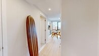 Located on Neptune Avenue in Brooklyn's Coney Island neighborhood, this one-bedroom, one-bathroom residence offers a thoughtfully designed coastal-inspired interior. Light oak hardwood floors run throughout, anchoring the open-plan living, dining, and kitchen area that serves as the heart of the home. Large windows flood the living room with natural light and frame expansive city views, creating an airy, elevated ambiance. The kitchen is outfitted with two-tone cabinetry — warm wood lowers paired with sleek white uppers — a marble-style backsplash, stainless steel appliances including a full-size refrigerator and professional-grade range, and ample counter space. The living area flows seamlessly into a dedicated dining space. The bedroom offers a serene retreat with large windows showcasing skyline views, light-toned walls, and continued hardwood flooring. The bathroom features floor-to-ceiling stone-tiled walls, a soaking tub with a sliding glass shower enclosure, a wood-vanity with an oval backlit mirror, and polished chrome fixtures. Three closets and a dedicated laundry area provide generous storage and convenience throughout this well-appointed Brooklyn residence.