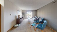 Located at 2804 Second St SW in Rochester, Minnesota, this single-floor residence offers a comfortable and functional layout designed for everyday living. The open-concept dining area is anchored by wood-look flooring and an elegant chandelier, seamlessly connecting to the kitchen, which features warm oak cabinetry, a subway tile backsplash, light hardwood flooring, and a full suite of stainless steel appliances including a refrigerator, dishwasher, microwave, and range. A half-wall pass-through adds an airy, connected feel between the kitchen and dining spaces. The living room is generously sized with plush carpeting and a large window with sliding door access to a private balcony, filling the space with natural light and outdoor views of surrounding trees. Two well-proportioned bedrooms each feature carpet flooring, windows with tree-lined views, and ample space. The primary bathroom includes a full tub-and-shower combination with warm wood vanity and wood-look tile flooring, while the secondary bathroom offers a standalone glass-enclosed shower with similar finishes. Throughout, the residence maintains a clean, neutral palette with textured ceilings and warm wood trim accents, creating a welcoming and practical living environment.