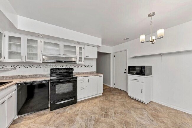 ¡Preciosa cocina renovada con armarios con puertas de cristal y mucho espacio de almacenamiento! Incluye todos los electrodomésticos: cocina, refrigerador, lavavajillas y microondas. La cocina se abre a una terraza acristalada, un encantador patio y un jardín trasero completamente cercado. - 11 Lawndale Ave