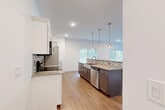 This single-floor space showcases a thoughtfully designed, modern interior with a cohesive aesthetic carried throughout. The kitchen serves as a standout feature, combining white shaker upper cabinets with rich dark-brown lower cabinetry and a contrasting island. Stainless steel appliances, including a range, over-the-range microwave, refrigerator, and dishwasher, complement the stone countertops and mosaic tile backsplash. A farmhouse-style sink anchors the island, which is illuminated by a trio of pendant lights. Multiple windows along the kitchen's far wall invite abundant natural light, while light wood-look flooring extends seamlessly into the open living area, which also benefits from dual windows with outdoor views.

The bedrooms feature plush patterned carpet and bright white walls, each with a window providing natural light and outdoor views. The bathrooms are finished with light wood-look tile flooring, dark-wood vanities topped with white countertops, large mirrors, brushed nickel fixtures, and a full tub-shower combination. The overall ambiance is clean, contemporary, and well-lit, reflecting a move-in-ready space with consistent, quality finishes.