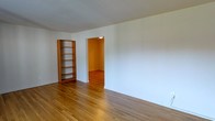 Located at 171 Main St in Madison, NJ, this single-floor space offers a clean, understated aesthetic that balances simplicity with functionality. The interior is defined by warm-toned hardwood flooring that runs throughout, lending a sense of continuity and warmth to the entire layout. Crisp white walls provide a bright, neutral backdrop that enhances the open feel of the space and allows for versatile use and personalization. A freestanding wooden bookshelf adds a touch of character and practical storage to the main room, complementing the natural wood tones of the flooring. An open doorway leads to an adjoining room, suggesting a connected, flowing floor plan that maximizes the use of available space. The secondary room, glimpsed through the doorway, is warmly lit and shares the same hardwood flooring, maintaining a cohesive aesthetic throughout. The overall ambiance is calm and inviting, with an emphasis on clean lines and an uncluttered environment. The single-floor layout ensures ease of movement and accessibility, making this a practical and welcoming space suited to a variety of needs.