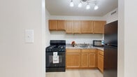 Located in the heart of Washington, DC, Unit 411 at 1225 L St NW offers a efficiently designed single-floor layout that includes a living room, kitchen, bathroom, and two closets. Throughout the unit, light-toned hardwood flooring creates a clean, cohesive aesthetic that enhances the sense of openness.

The living area is bright and airy, anchored by a large sliding glass door dressed with vertical blinds that allow natural light to filter in while providing views of the surrounding cityscape. The open layout offers flexible furniture arrangements to suit a variety of living styles.

The kitchen is well-appointed with warm honey-toned wood cabinetry, granite-style countertops, and a full suite of black appliances including a gas range, refrigerator, and microwave. A track lighting fixture overhead ensures ample illumination, and the light flooring continues seamlessly from the main living space.

The bathroom features white subway-style tile surrounding a full soaking tub and shower combination, complemented by mosaic tile flooring and a wood-toned vanity with a dark granite countertop. Two closets provide practical storage solutions throughout the unit.

The overall ambiance is clean, modern, and functional, with a neutral white color palette that creates a bright and welcoming atmosphere throughout this conveniently located Washington, DC residence.