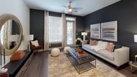 This contemporary single-floor residence is designed with a refined aesthetic and thoughtful layout. The open-concept kitchen is a standout feature, showcasing dark espresso cabinetry with glass-front upper panels, stainless steel appliances including a range, microwave, and dishwasher, dark granite countertops, and a glass tile backsplash with under-cabinet lighting. A kitchen island with pendant lighting and bar seating connects seamlessly to the living and dining areas, making it ideal for entertaining.

The living area exudes a bold, modern character with deep charcoal accent walls, rich dark hardwood flooring, and large windows and a glass door that invite generous natural light and outdoor views. A ceiling fan adds comfort and function to the space.

The bedroom offers a serene retreat, featuring plush carpet flooring, soft neutral walls, a ceiling fan, and a large window that fills the room with natural light. The space is generously proportioned and includes access to a walk-in closet with built-in shelving and hanging rods for organized storage.

The bathroom features a glass-enclosed walk-in shower with large-format tile surround and chrome fixtures, reflecting a clean, contemporary finish throughout. The overall ambiance of the space is modern, cohesive, and move-in ready.