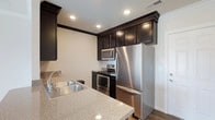 Located at 3381 Blue Heron Dr in Hilliard, Ohio, this single-floor residence offers a well-designed layout with a clean, contemporary aesthetic. The kitchen stands out as a centerpiece of the home, showcasing rich dark cabinetry that extends to the ceiling for ample storage, complemented by sleek granite countertops with a subtle speckled finish. Stainless steel appliances — including a full-size refrigerator, gas range, and built-in microwave — lend a polished, modern look throughout the space. Recessed lighting illuminates the kitchen evenly, highlighting the quality finishes and creating a bright, functional atmosphere. A double-basin stainless steel sink is positioned conveniently along the counter, adding to the kitchen's practical design. The neutral wall tones and light hardwood-style flooring provide a warm, inviting backdrop that ties the space together cohesively. The single-level floor plan offers ease of navigation and a comfortable, accessible living environment. Overall, this Hilliard home presents a thoughtfully appointed interior with modern finishes that balance style and everyday functionality.