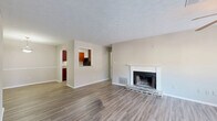 Located at 115 Rock Quarry Rd in Stockbridge, GA, this single-floor, 2-bedroom, 2-bathroom home offers a well-organized layout designed for comfortable everyday living. The living room serves as the heart of the home, showcasing a wood-burning fireplace with a classic stone hearth and white mantel, durable laminate flooring, a textured ceiling, and a ceiling fan. A wide bank of windows floods the space with natural light and provides outdoor views, creating an inviting atmosphere. The living area flows seamlessly into the dining room, which features a pendant light fixture, and connects to the kitchen via a convenient pass-through window. The galley-style kitchen is well-appointed with rich cherry wood cabinetry, granite countertops, a gas range, dishwasher, and a stainless steel sink. Both bedrooms are carpeted and bright, each featuring windows that let in natural light. The primary bedroom includes a dedicated closet with built-in shelving. Both bathrooms are finished with laminate flooring, tub/shower combinations, and clean, neutral tones. Additional practical features include four closets for generous storage, a dedicated laundry room, and a central hallway connecting all spaces efficiently throughout the home.