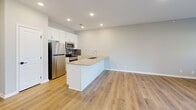 Located at 18683 Oakmont Dr in Omaha, Nebraska, this well-appointed 1-bedroom, 1-bathroom home offers a thoughtfully designed single-floor layout with modern finishes throughout. The open-concept kitchen and living area serves as the heart of the home, featuring durable wood-look plank flooring, recessed lighting, and a seamless flow between spaces. The kitchen is outfitted with crisp white cabinetry, a decorative tile backsplash, stainless steel appliances — including a refrigerator, range, and built-in microwave — and a peninsula with a granite-style countertop and double undermount sink, ideal for both meal prep and casual dining. The living area is bright and airy, benefiting from natural light provided by a side window and sliding glass doors that open to a patio with views of the surrounding green space and community. The bedroom offers a comfortable retreat, finished with plush carpet, a ceiling fan, and a window that allows additional natural light. A dedicated closet provides convenient storage. The full bathroom is cleanly finished with a white vanity, granite-style countertop, tub-shower combination, and wood-look flooring that ties the space together. A hallway connects the rooms efficiently, completing this clean and functional floor plan.