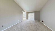 Located at 2400 North Blvd in Houston's 77098 zip code, this single-story residence at The Boulevard offers a well-organized layout encompassing three bedrooms, one full bathroom, a living room, and a dedicated closet. The living area features notable vaulted ceilings that lend an open, airy feel, complemented by soft carpet flooring and neutral gray walls throughout. Vertical blinds cover a large sliding door, allowing natural light to filter in while maintaining privacy. A secondary window in the living space further brightens the interior. The bedrooms are carpeted and receive natural light through large windows fitted with horizontal blinds; one bedroom includes a ceiling fan and direct access to the bathroom. The spacious walk-in closet is outfitted with wire shelving systems on three walls, providing ample storage and organization. The full bathroom features dual sinks with a long vanity, wood-trimmed cabinetry, dual medicine cabinets with lighted mirrors, a tub-shower combo with tile surround, and wood-look vinyl flooring. Built-in shelving in one bedroom area adds additional storage convenience. The overall palette of soft grays and whites creates a clean, neutral ambiance throughout the home.