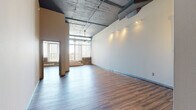 Located at 1516 Cuming St in downtown Omaha, this two-bedroom, two-bathroom loft unit delivers a striking industrial-modern aesthetic across a generously sized single-floor layout. The open-concept living and kitchen area immediately impresses with soaring ceilings, exposed concrete and visible ductwork overhead, and rich hardwood-style flooring that runs throughout the space. Large windows flood the living area with natural light and offer urban views of the Omaha skyline, enhancing the loft's airy, expansive feel.

The kitchen is defined by warm wood cabinetry, granite-look countertops, a peninsula breakfast bar, and a full suite of stainless steel appliances including a refrigerator, range, microwave, and dishwasher. Pendant lighting adds a refined touch above the workspace. Track lighting is featured throughout the unit, complementing the industrial character of the ceilings.

The primary bedroom is spacious, with tall ceilings and hardwood-style flooring continuing from the main living areas. A walk-through closet provides ample storage with built-in shelving and hanging rods. The second bedroom is well-proportioned and equally bright. A hallway connects the private quarters to the rest of the unit, and a dedicated closet offers additional storage. Two full bathrooms complete this well-appointed urban residence.