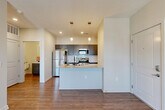 Located at 17821 Cypress Dr in Omaha, Nebraska, this 1-bedroom, 1-bathroom unit offers a thoughtfully designed single-floor layout that maximizes every square foot. The open-concept kitchen and living area forms the heart of the home, where warm wood-look flooring flows throughout. The kitchen is outfitted with grey shaker-style cabinetry, granite-look countertops, a white subway tile backsplash, stainless steel appliances — including a refrigerator, electric range, and built-in microwave — and a peninsula with a double-basin sink featuring a matte black faucet. The living area is bright and airy, benefiting from natural light and direct access to a private balcony through a glass door. The bedroom is carpeted for comfort, features a ceiling fan, a generous window with neighborhood views, and is accompanied by a dedicated closet for ample storage. The bathroom is clean and modern, with wood-look flooring, a walk-in shower with white surround, and matte black hardware and fixtures throughout. Neutral wall tones and consistent finishes create a cohesive and move-in-ready atmosphere across the entire space.
