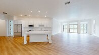 Located in Oakmont, PA, this thoughtfully designed single-floor home offers four bedrooms and four bathrooms across a generous and well-appointed layout. The open-concept kitchen and living area serves as the heart of the home, showcasing warm light hardwood flooring, recessed lighting, and a large central island with elegant marble-style countertops. Crisp white shaker cabinetry lines the kitchen walls alongside stainless steel appliances, including a premium range and built-in microwave. The living room extends naturally from the kitchen and is bathed in natural light through a bank of large windows and glass doors that open onto a private balcony overlooking lush greenery. Crown molding adds a refined touch to the living space. The generously sized primary bedroom features plush carpeting, a walk-in closet, and access to an en-suite bath. Three additional bedrooms, also carpeted, offer comfortable accommodations. The bathrooms are finished with neutral tile flooring, white vanities with sleek countertops, and tub-shower combinations. Three hallways connect the spaces efficiently throughout the home. Clean white walls and consistent finishes throughout create a bright, cohesive, and modern ambiance.