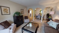 This single-story residence offers a well-organized layout across two bedrooms and one bathroom. The living room serves as the heart of the home, featuring plush carpeting, a textured ceiling, and a sliding glass door that fills the space with natural light while providing access to an outdoor patio. Distinctive arched doorways connect the living area to the dining room and beyond, lending architectural character throughout.

The dining room accommodates a full dining set and is topped with a ceiling fan, with direct access to the kitchen. The kitchen is equipped with ample cabinetry, a double-basin sink, wood-style flooring, and black appliances including a range, dishwasher, and refrigerator, offering both functionality and storage.

The primary bedroom is a generously sized, carpet-floored retreat with neutral tones and a bright window. The second bedroom comfortably fits multiple beds and also benefits from natural light through a large window. The shared bathroom includes a vanity with countertop storage, a toilet, and a shower-tub combination with tile surround and wood-style flooring, completing this cohesive and practical floor plan.